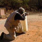 Bob Campbell shootign a shotgun from behind a barrel