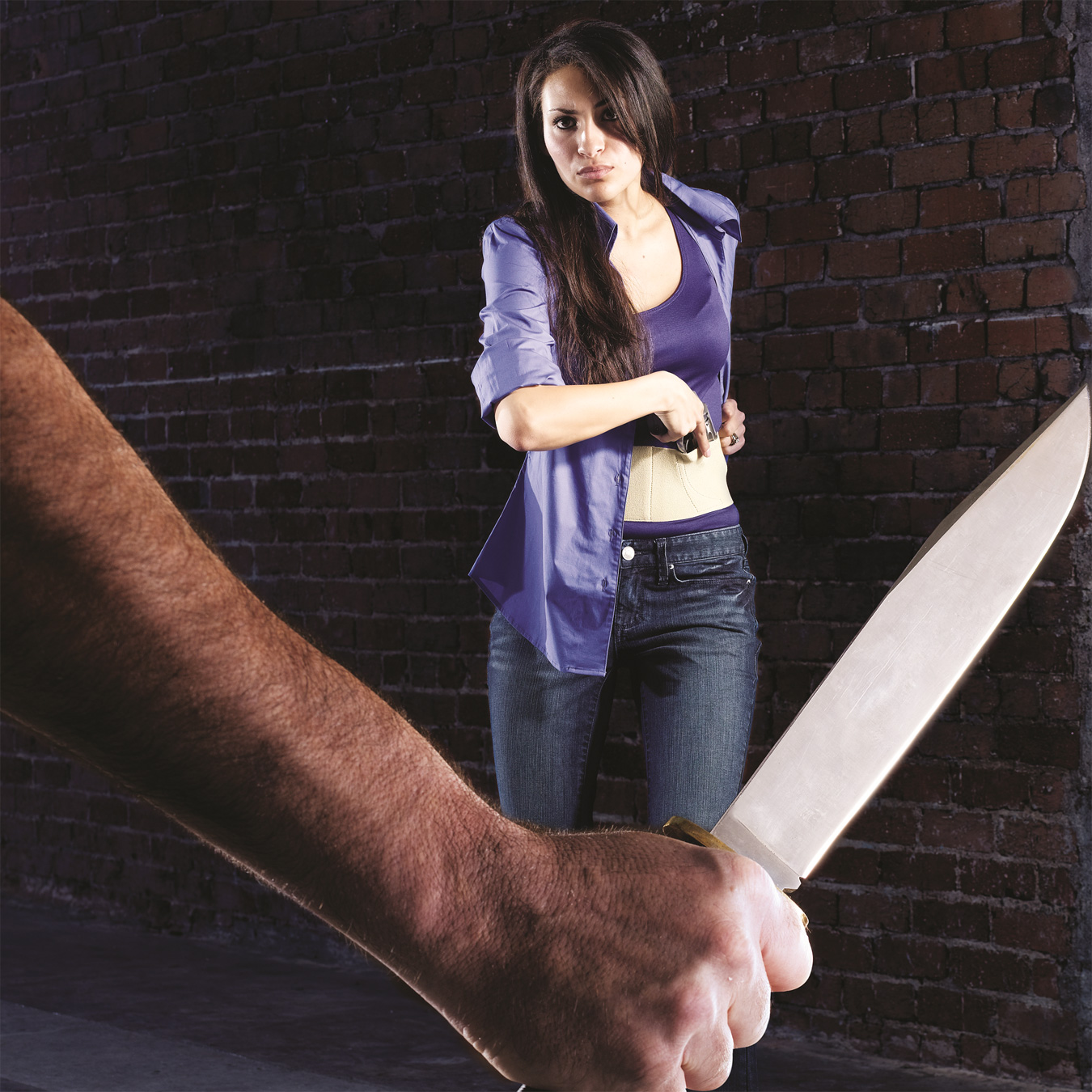 hand holding a knife while a woman draw a pistol from a belly band holster