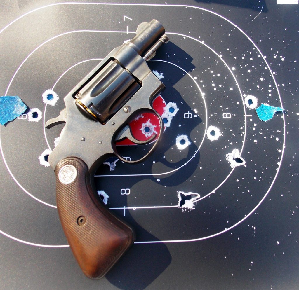 Revolver atop a target with multiple bullet holes