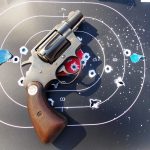 Revolver atop a target with multiple bullet holes