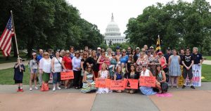 A girl & a gun women's group posing in front of the capital building with protest signs 