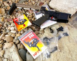 AR-15 on a bed of river rock with two Hipertouch triggers in the packaging