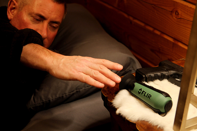 man in bed reaching for a Scout TK handheld thermal camera