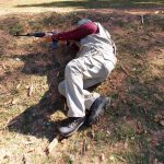 Man firing a rifle while laying on his side using topography for cover