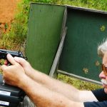 Bob Campbell firing a pistol from a braced position