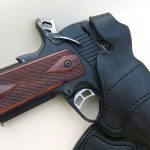 1911 pistol cocked and locked in a black leather holster
