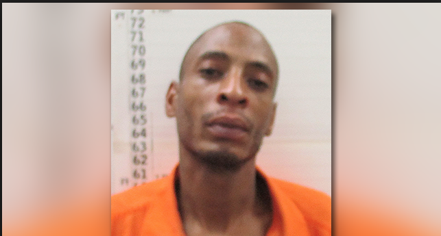 Booking photo of black man wearing an orange jump suit.
