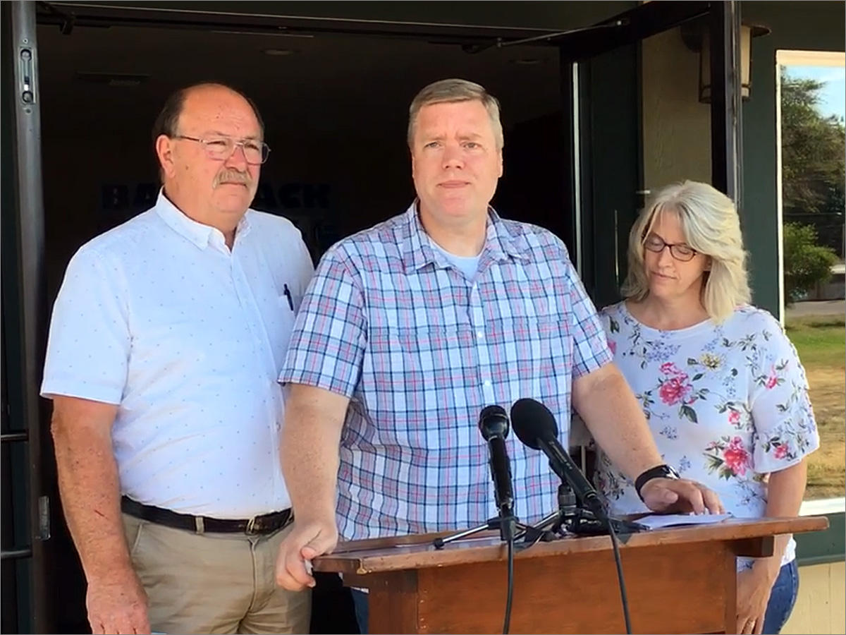 Pastor David George, flanked by his wife and the Oakville, Washington, fire chief