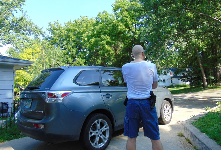 Dean Weingarten standing next to a car openly carrying a pistol in a holster for open carry