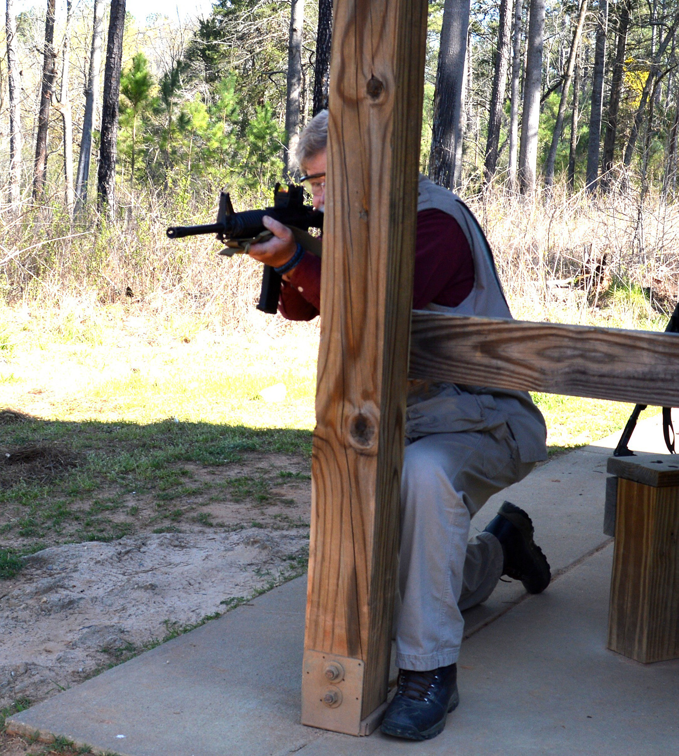 Man firing an AR-15 from behind a wood post