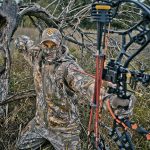Bowhunter at full draw wearing camouflage clothing