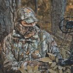 hunter sitting at the base of a tree