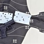 silhouette target with white 3x5 cards filled with bullet holes