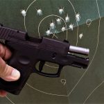 Taurus G2S posed with a target filled with bullet holes