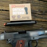 Colt 1911 with slide locked back and a box of Hornady Critical Defense ammunition