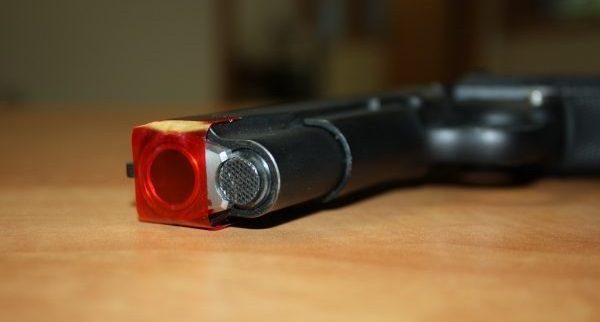 handgun with red tape over the barrel mocking gun control