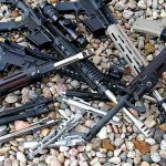 Several AR-15 laying on a bed of rocks