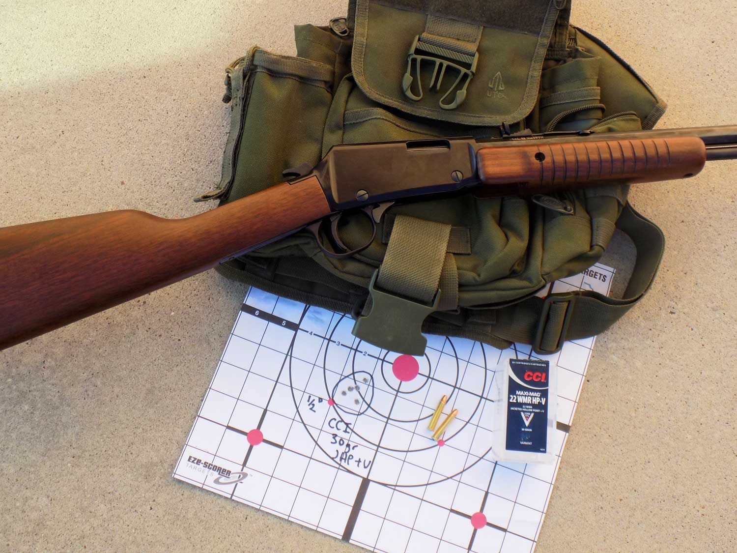 Henry Pump Octagon rifle over an olive drab colored pouch and paper targets