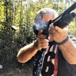 Bob Campbell shooting a shotgun as a shell is being ejected