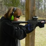 Woman shooting arifle equipped with a red dot sight