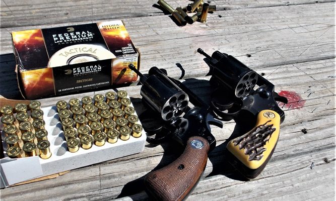 Two revolvers with open cylinders and an ammunition box