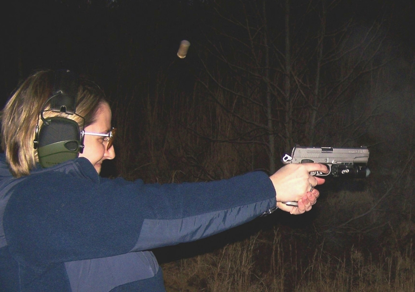 woman shooting a handgun at night