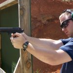 Man firing a pistol from a braced position