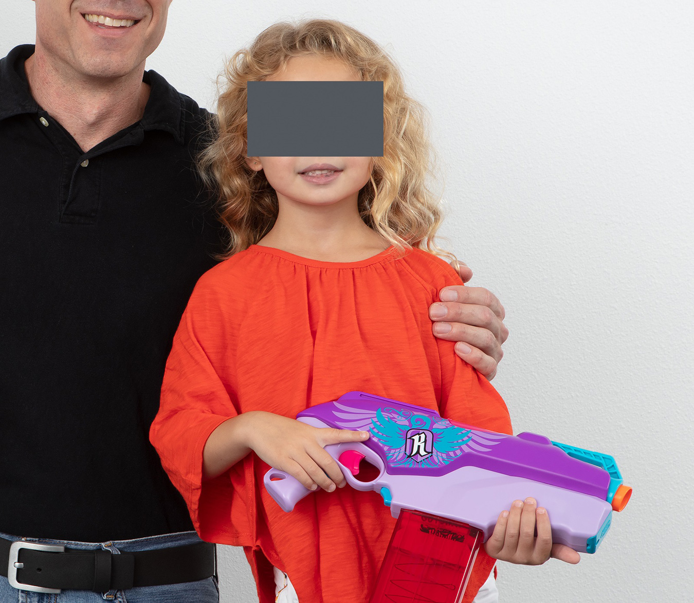 Father posing with daughter who is holding a toy dart gun