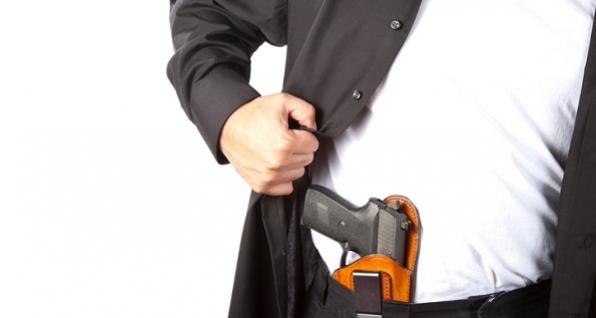 Man pulling back his suit jacket to reveal a gun in a holster