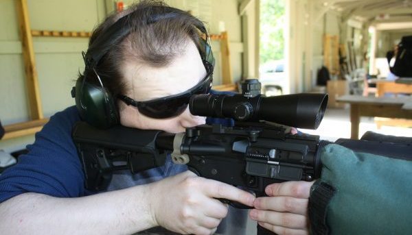 Man shooting an AR-15 rifle from a benchrest to protest a gun buyback program