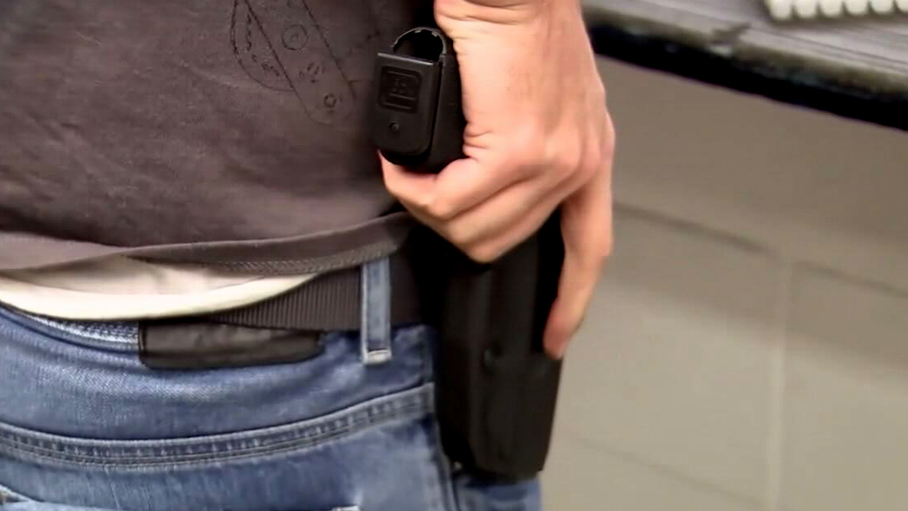 Man with his hand on a holstered pistol preparing to draw