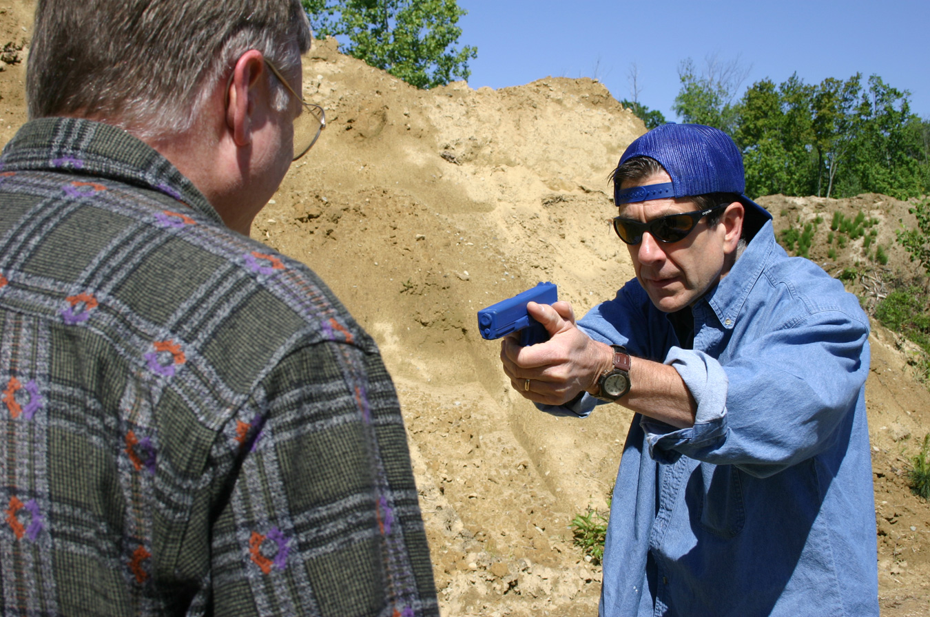 Man being robbed at gun point initiating his survival instinct