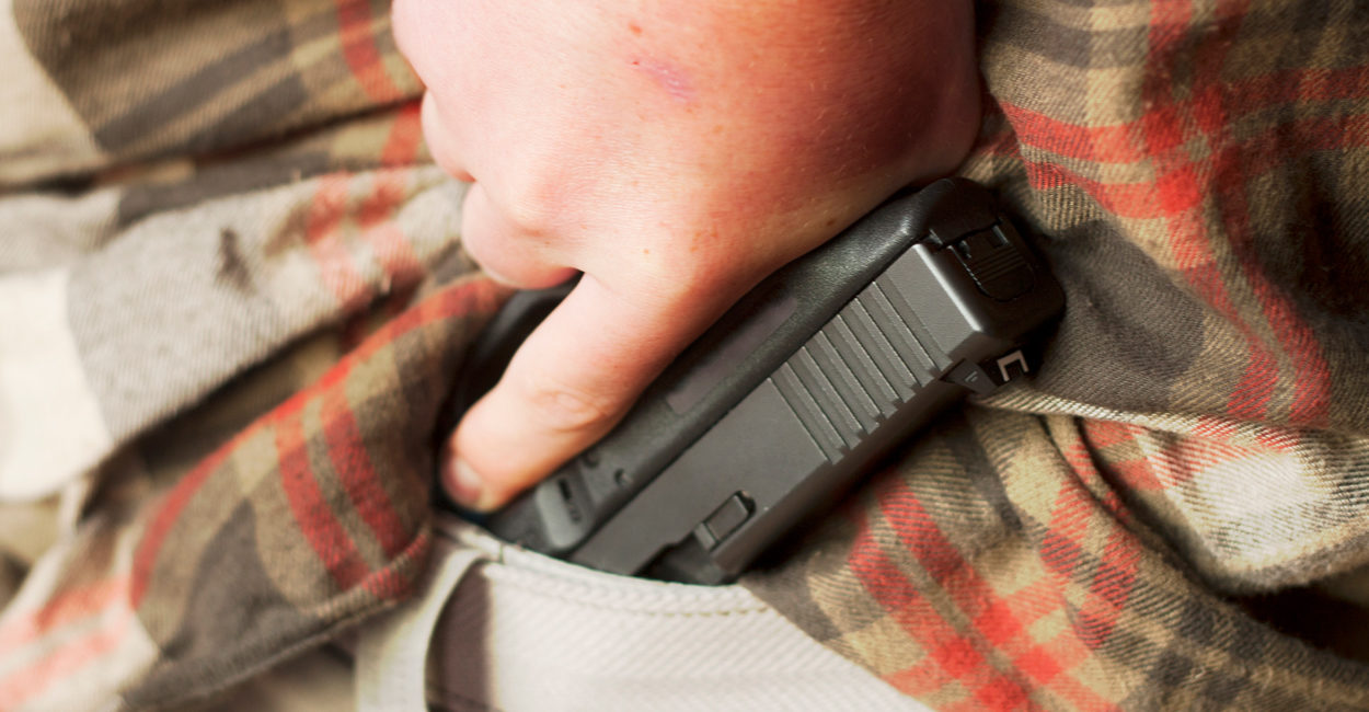 Concealed handgun being drawn from waistband