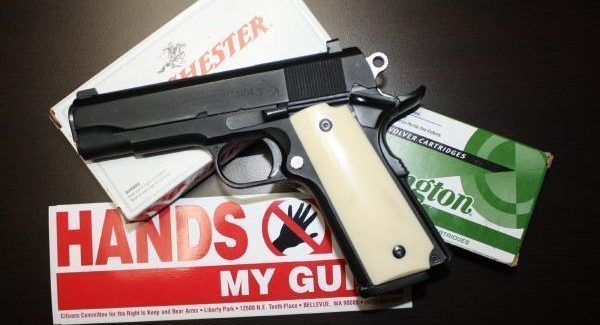 1911 handgun over several boxes of ammunition with gun control sticker