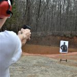 Young man aiming the Taurus TX22 pistol with a target in the foreground