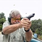 Bob Cambell shooting a pistol with spent cartridge cases in the air