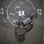Revolver on a black silhouette target riddled with bullet holes