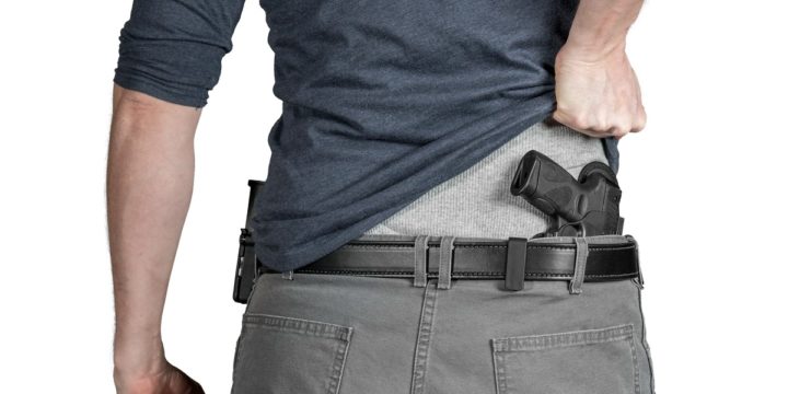 Man lifting his shirt to expose a concealed handgun