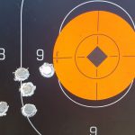 Silhouette target with orange center showing bullet hole grouping