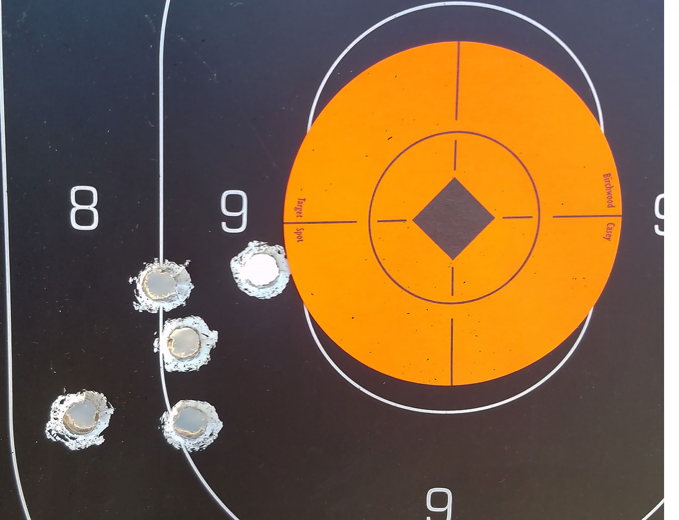 Silhouette target with orange center showing bullet hole grouping