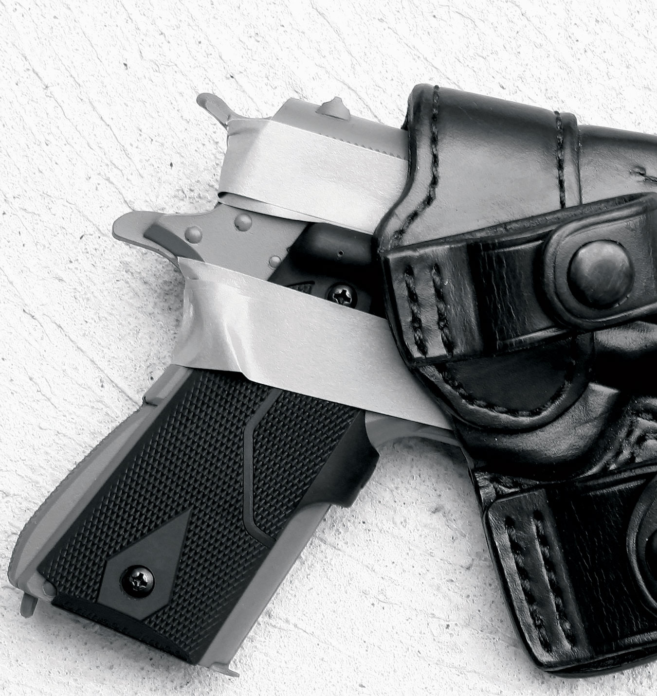 handgun with masking tape around it inserted into a black leather holster