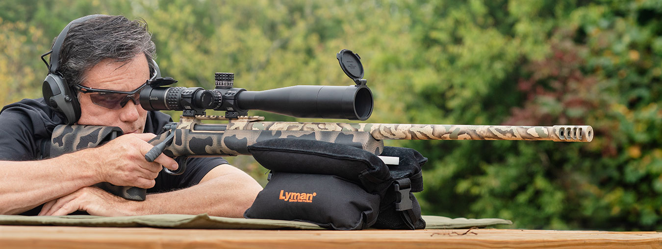 Man shooting a bolt action .30 caliber rifle from a shooting bench