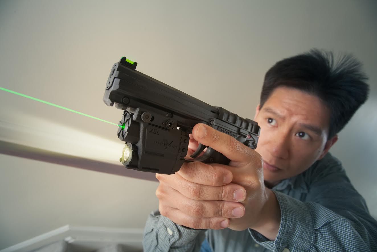 Asian man holding a pistol with a green laser beam