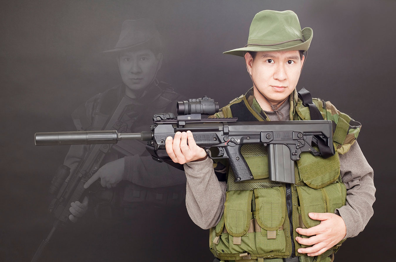 Asian man in battle dress holding an assault rifle, something that is not available in Hong Kong