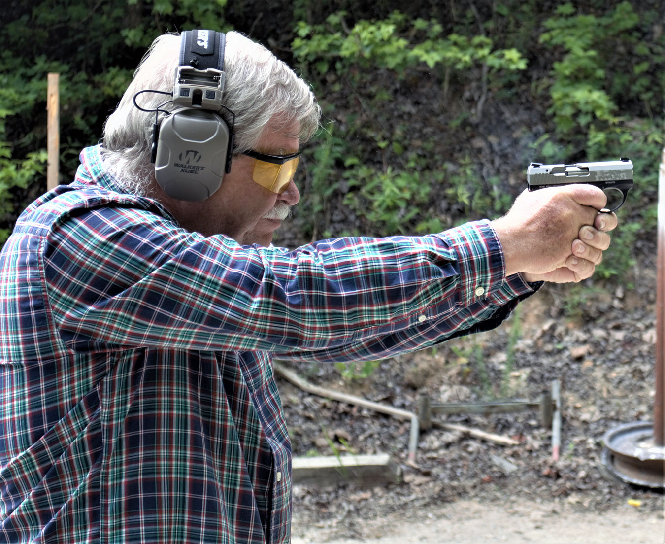 bob Campbell shooting a pistol with a two-handed grip