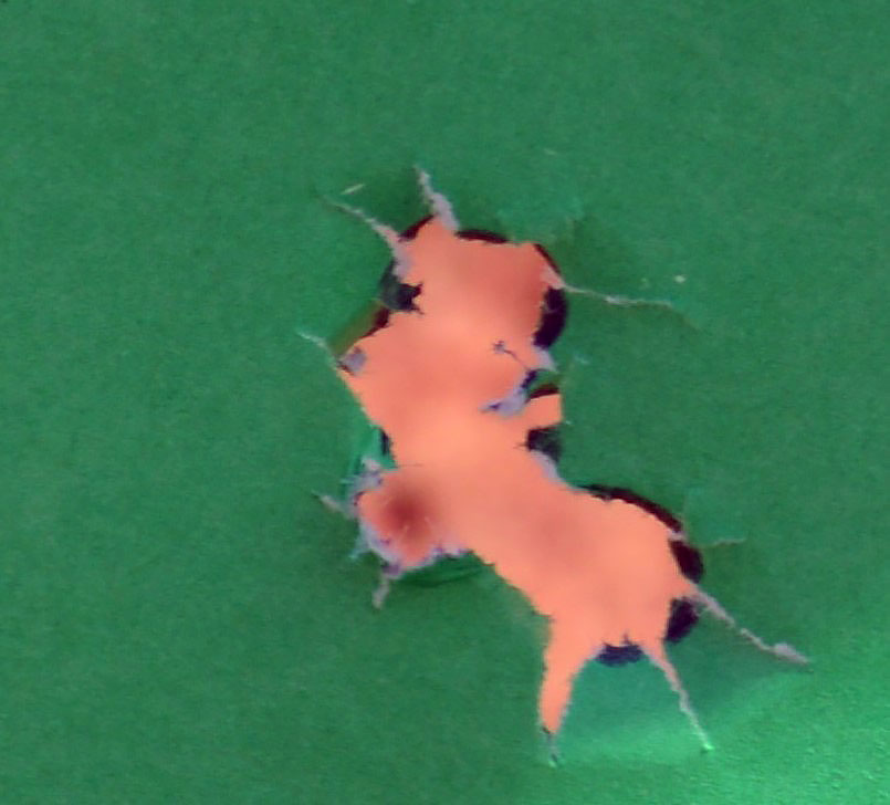 Four bullets holes combined into one ragged hole to show accuracy