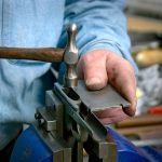 Fitting the slide to the frame of a 1911 pistol with a small hammer, close up