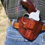 revolver in a leather holster worn on a belt at the small of the back position