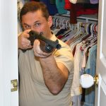 Man hiding in a closet with a shotgun pointed out of the door