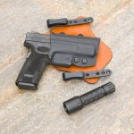 Springfield Armory XD45 in a leather and Kydex holster with a small black flashlight next to it